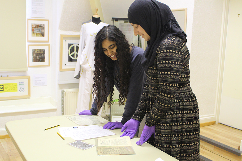 Image 1: Hanna Ahmed (left) and Nazish Majid looking at items from the archive at The Peace Museum, Bradford