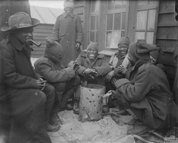 Troops of the South African Native Labour Corps around a brazier at their camp. Dannes, March 1917. © IWM (Q 4875)