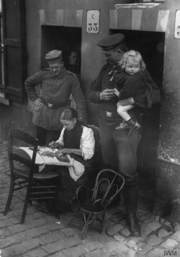 German soldiers watching a female lacemaker at work in German occupied Belgium